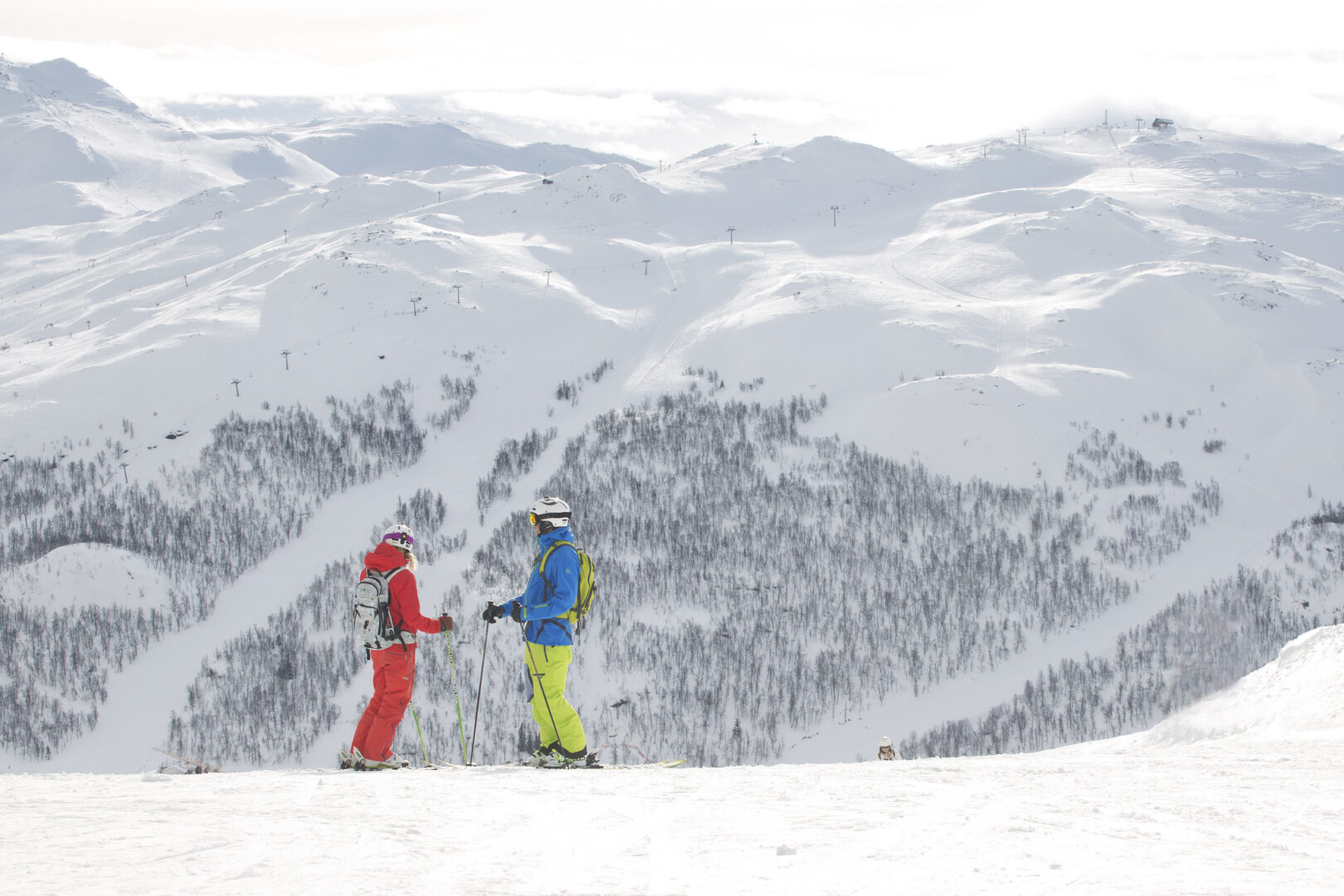 Pister i Hemsedal med to mennesker på toppen af fjeldet og udsigt til skicenteret